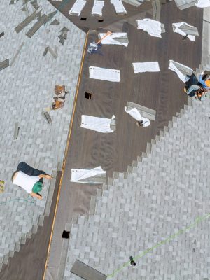 Roofer working on replacement asphalt shingle roof construction